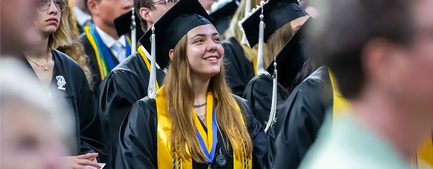 A smiling girl in a graduation gown during the commencement ceremony.